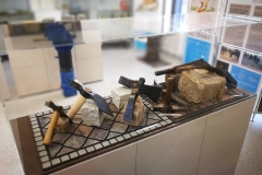 Vititrine der Ausstellung mit Pflasterhämmern
